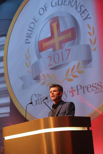 Corporate event host Carl Ward presenting live on stage for the local Pride of Guernsey Awards ceremony.
